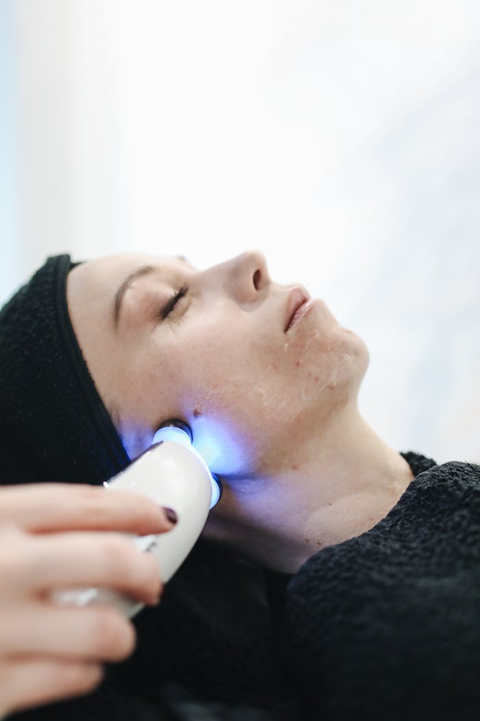 A woman enjoying a relaxing facial treatment with a skincare device at a spa.